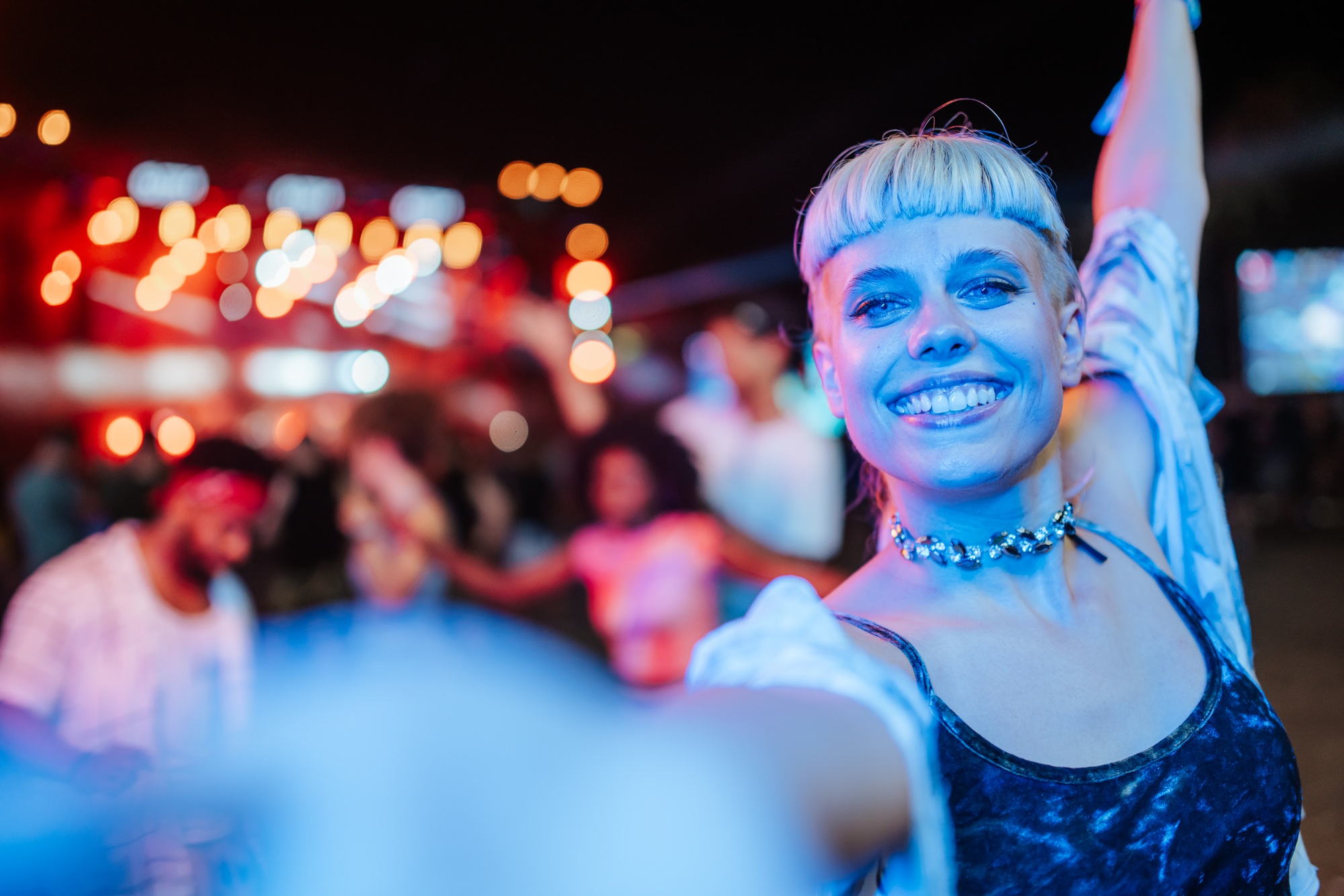 Young woman taking selfie at night concert, enjoying live music event