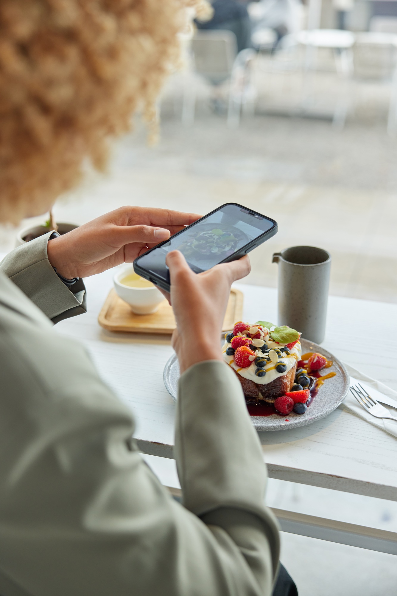 Cropped image of female influencer makes photo of food for social networks eats delicious dessert in