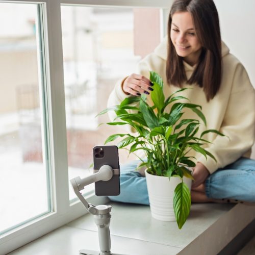 Young beautiful woman influencer blogger blogging about houseplants